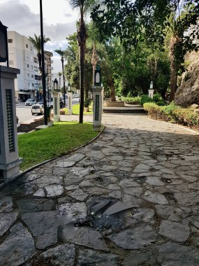 Döşemeleri kayalar, güneş ışığı ve gölgelerle süslenmiş sütunlar. Mozaik desenlerdeki döşemeli sütunlar manzaraya meydan okuyor, şehrin ortasında kayalarla sıralanmış bir yol var.