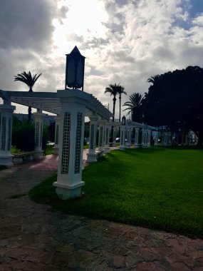 Dolambaçlı bir yoldaki parlak beyaz sütunlardaki desenler, yol boyunca nöbet tutarlar, doğanın şefkati onları yumuşatır. Huzurlu atmosferin tadını çıkarmak için yeşilliğin ortasında bulunan çekici banklar.