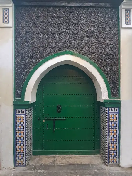 stock image Step into a world of Moorish elegance as you encounter a striking green wood door adorned with Moroccan zellij decoration around it. This captivating entrance exudes the timeless charm of Moroccan craftsmanship, with the green wood complementing the 