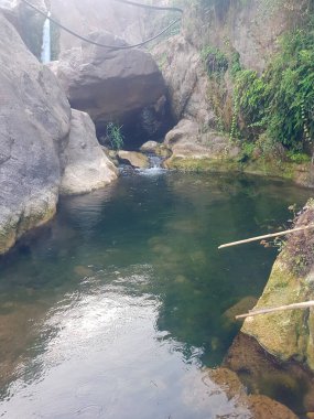 Fas dağlarında çarpıcı bir gölet. Gölet yemyeşil ve kayalarla çevrilidir. Fotoğraf doğal ortamın güzelliğini ve huzurunu yakalıyor.