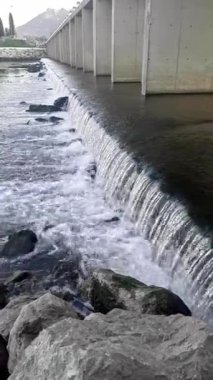 Geniş şelale vadideki bir köprünün altında yer almaktadır. Akan suyun yakın bir görüntüsü.