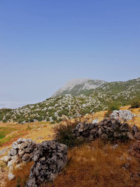 Uzakta görünen Kelti Dağı ile sakin bir dağ manzarası açılır; açık, güneşli bir sonbahar akşamı, meşe ağaçlarının arkasındaki dolambaçlı sırt çizgilerini takip edin.