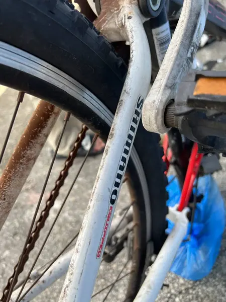 Eski motosiklet, yaz mevsiminde bir sokak parkına park edilmiş.