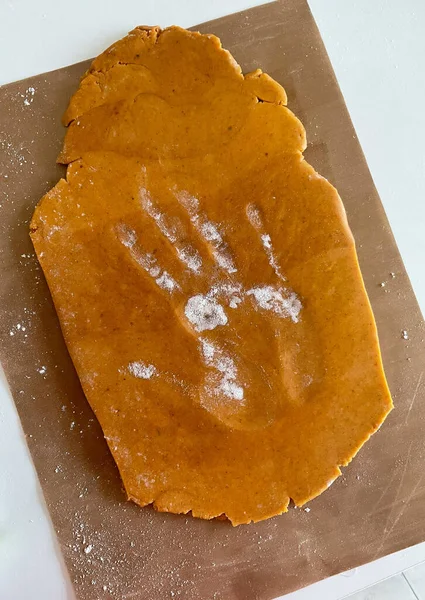 Photo of gingerbread dough with palm print. The background is simple. High quality photo in daylight. On the white table.