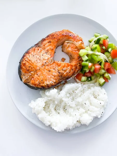 Healthy balanced meal lunch plate - baked salmon with rice and vegetables on a light background, top view