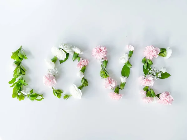 The word LOVE from flowers on a white background. Spring concept. flat lay