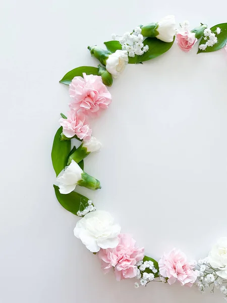 stock image Round frame of pink and white carnations, green leaves, gypsophila on a white background. Flat lay, top view. Spring background. Suitable for wedding, cards and invitations