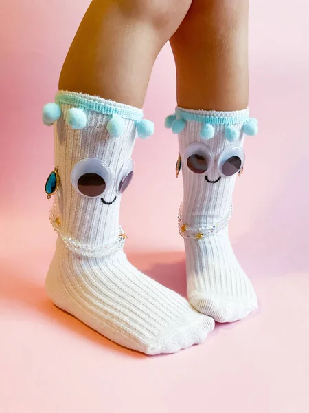 ピンクの背景に目と笑顔で赤ちゃんの靴下 子供の足の上に目や装飾とかわいい面白い靴下 — ストック写真