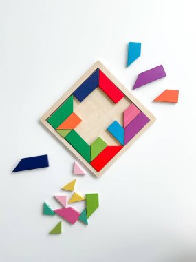 Tangram oyunu. Çok renkli parçalar beyaz masada parçalarına ayrılır. Beyaz arkaplanda üst görünüm. Yüksek kalite fotoğraf