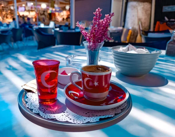 Coffee in red cup with the flag of Turkey and vase of flowers on table in a cafe. High quality photo