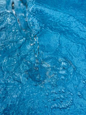 Background dynamic splash of clear water creating swirling wave in blue water with droplets suspended in motion. Clean water concept. High quality photo clipart