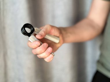 Siyah ve gümüş el genişleticiyi tutan adama yaklaş. Arka planı bulanık olan kalemi tutmaya odaklan. Spor anlayışı, spor anlayışı ve evde sağlıklı yaşam tarzı. Yüksek kalite fotoğraf