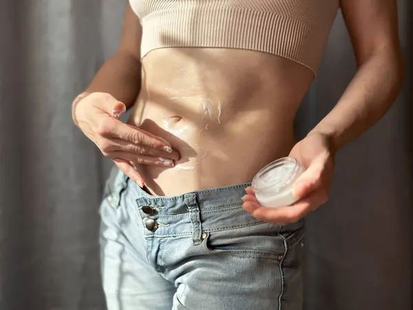 stock image Close up of slim woman applying cream to her bare stomach. Concept of skincare, self care, and body care routine. Lifestyle photo. High quality photo