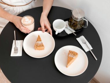 Yuvarlak bir masada çay ve pasta dilimleri ile rahat bir kafe..