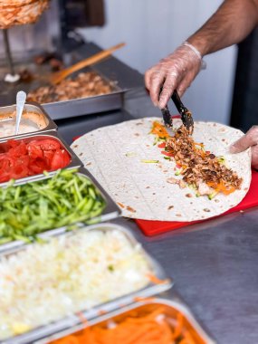 Şef mutfakta canlı sebzelerle taze shawarma dürümü hazırlıyor..