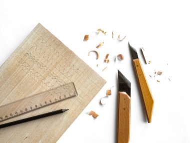 Beyaz arka planda ahşap oyma araçları ve talaşlar.