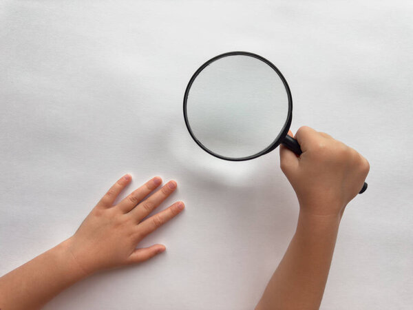 Чайлдсу любопытно. Рука держит лупу над белой поверхностью.