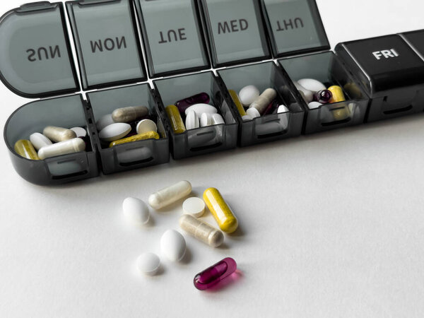 Organized weekly pill box with assorted medications and supplements.