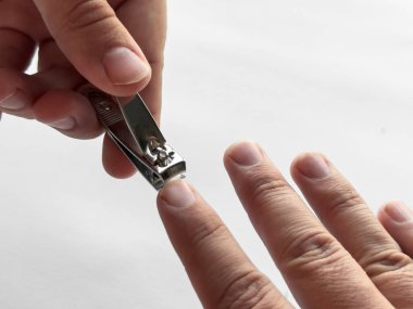 Beyaz arka planda kişisel bakım için tırnak makasıyla elinizi kapatın.