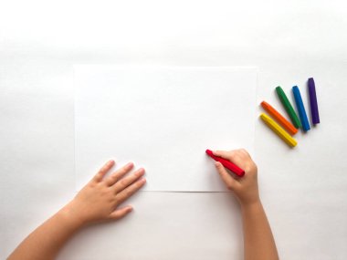 Beyaz kağıda parlak boya kalemleri çizen çocuk..