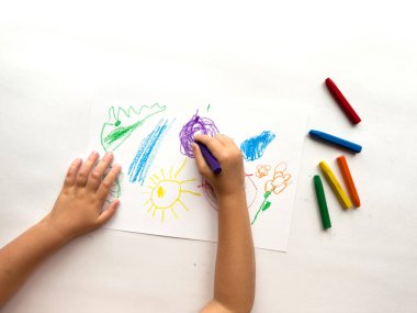 Beyaz kağıda renkli boya kalemleri çizen çocuk..