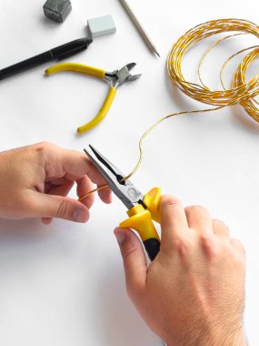 Eller beyaz yüzeyde diy projesi için araçları ile tel budamak için pense kullanıyor.