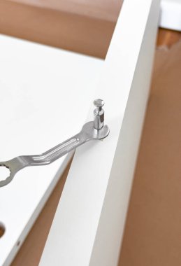 Beyaz mobilyaları metal anahtarla birleştirmek ve kahverengi yüzeye kamera kilidi takmak.