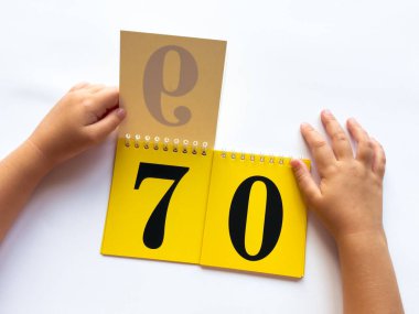 Childs 'ın elleri sarı sayfaları numaralarla çeviriyor. Beyaz arkaplanda 70 numarayı göster.