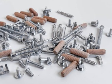 Beyaz yüzeyde çeşitli metal vidalar ve ahşap kaplamalar.