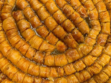 Sıraya dizilmiş taze fırınlanmış baklavanın katı arkaplanı, şuruplu altın kahverengisi, geleneksel Orta Doğu tatlı tatlısı, dokusu yakın. Ramazan konsepti. Yüksek kalite fotoğraf