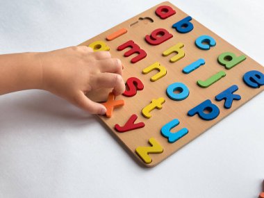 Childs ahşap tahtada renkli alfabe bulmacası düzenliyor.