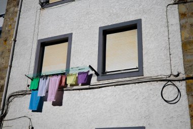 Şehir duvarında asılı renkli çamaşırlar ve kapalı pencereler..