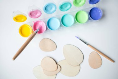 Renkli pastel beyaz arka planda ahşap şekilli boya ve fırçalar.