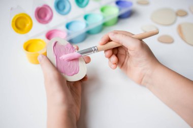 Paskalya tahtasını pembe boyayla boyayan çocuk, Kafkas, genç, sanat aktivitesi, yaratıcılık.