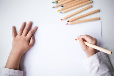 Childs 'ın elleri beyaz kağıda renkli kalemler çiziyor..