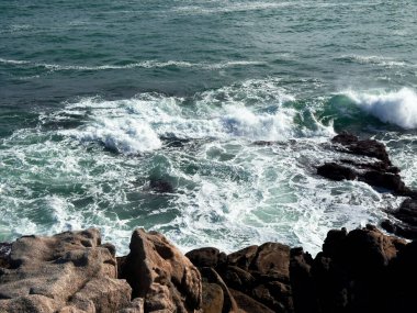 Muhteşem okyanus dalgaları gün batımında kayalık kıyı şeridine çarpıyor..
