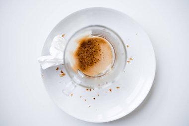 Boş kapuçino bardağı beyaz tabakta kırıntılar ve mendille.
