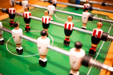 Yeşil sahada kırmızı ve beyaz oyuncu figürleri olan masa üstü futbol oyunu.
