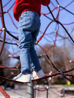 Güneşli bir günde ipe tırmanan beyaz bir çocuk..