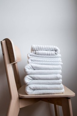 Minimalist ortamda tahta sandalyeye yığılmış beyaz havlular..