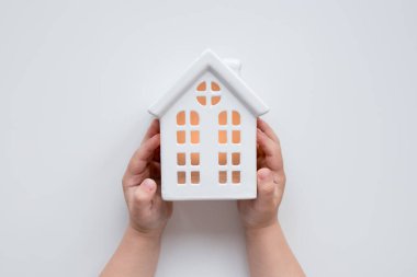 Seramik ev modelini tutan çocuk, odada sıcak bir parıltı var..