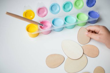 Paskalya ahşap yumurtalarını renkli akrilik boya ve fırçayla boyayan çocuk..