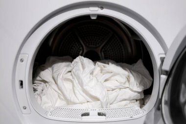 Modern çamaşır kurutma makinesindeki beyaz çarşaflar çamaşır sahnesini kapatır..