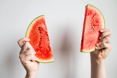 Beyaz arka planda karpuz dilimleri tutan eller.