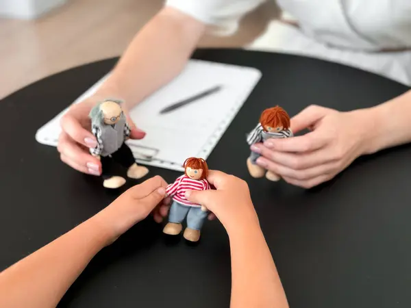 Masadaki kukla aile etkileşimiyle çocuk terapisi seansı.