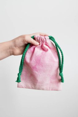 Beyaz arka planda yeşil ipli pembe ipli çanta..