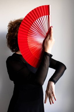 Kırmızı yelpazeli, zarif siyah elbiseli bir bayan dansçı..