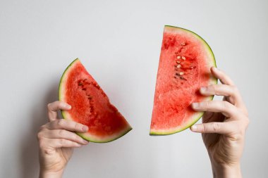 Dilimlenmiş karpuzu beyaz arka planda tutan eller..