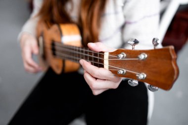 Beyaz kadın parmak karıştırma tekniğine odaklanmış ukulele oynuyor..