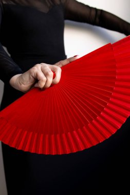 Siyah elbiseli, kırmızı yelpaze tutan bir kadın..